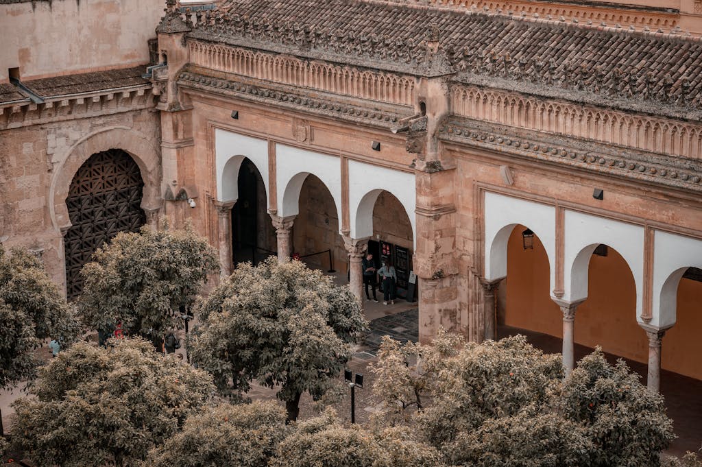 Aerial view of the historic Mosque-Cathedral of Córdoba with its iconic arches and surrounding trees.